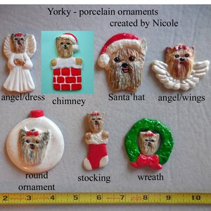 May include: A collection of Yorky porcelain ornaments, including an angel, chimney, Santa's hat, angel with wings, round ornament, stocking, and wreath. The ornaments are created by Nicole and feature a Yorky dog design.
