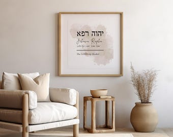 May include: A framed print with a watercolor background in shades of pink and beige. The print features the Hebrew word "Jehovah Rapha" in black text, which translates to "The Lord my Healer".