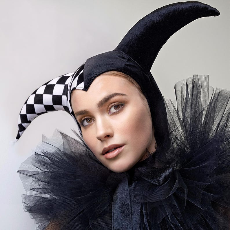 Pu&ograve; includere: Una donna con un cappello da giullare bianco e nero con un colletto di tulle nero.