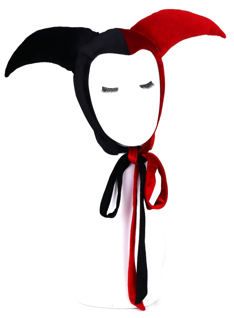 Pu&ograve; includere: Un cappello da giullare nero e rosso con lunghi lacci. Il cappello ha due punte sulla parte superiore ed &egrave; fatto di velluto.