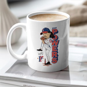 Puede incluir: Taza de cerámica blanca con una ilustración de dibujos animados del jugador de béisbol Kenny Powers con un uniforme de béisbol rojo, blanco y azul. El texto "Kenny Powers" está escrito en letras azules y rojas en la taza.