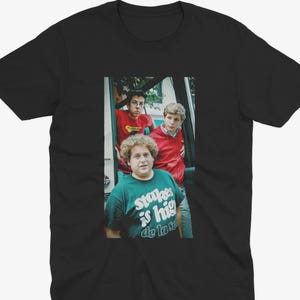 May include: A white ceramic mug with a black handle and the text "But First, Coffee" in a black, bold font. The mug is sitting on a wooden surface. The mug is approximately 4 inches tall.