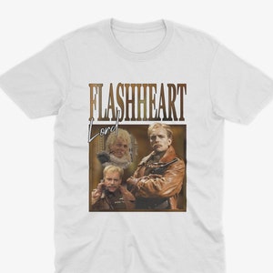 May include: White t-shirt with a vintage-style graphic featuring the text "FLASHHEART Lord" and a photo of three men.
