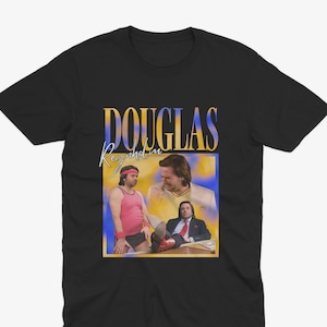 Może przedstawiać: Czarny T-shirt z grafiką w stylu vintage przedstawiającą zdjęcie trzech mężczyzn. Grafika zawiera tekst "DOUGLAS Reynolds" w żółtej i niebieskiej czcionce.