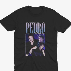 May include: Black t-shirt with a graphic of Pedro Pascal in a retro style. The graphic features a collage of three images of Pascal with the text "PEDRO Pascal" above the images.
