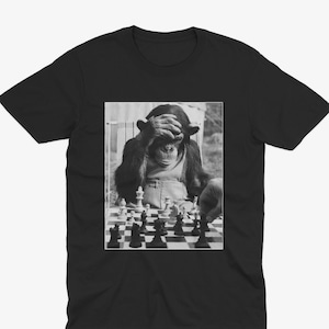 May include: A black and white photograph of a chimpanzee playing chess. The chimpanzee is covering its eyes with its hand, as if it is thinking about its next move. The chessboard is in the foreground, and the chimpanzee is sitting in a chair in the background.