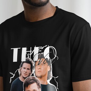 May include: Black t-shirt with a white graphic print of three men's faces and the text "THEO" in a stylized font.