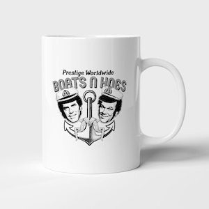 May include: White ceramic mug featuring a black and white graphic. The design includes the text "Prestige Worldwide" above "Boats N Hoes", along with two men's faces and an anchor.