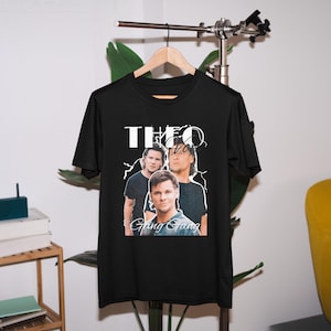 May include: Black t-shirt with a white graphic of three men with the text "Theo Gang Gang" printed on it.