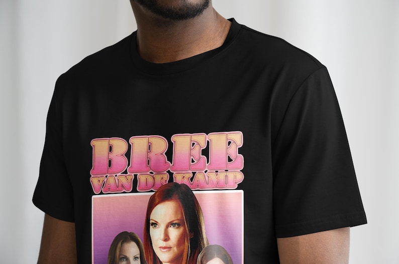May include: Black t-shirt with a pink and yellow graphic print that says "Bree Van de Kamp". The graphic also features a woman with long brown hair.