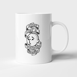 Peut inclure: Mug en céramique blanche avec une illustration en noir et blanc. Le design présente une tête de dessin animé avec le texte "HEAD LIKE A FUCKING ORANGE" dans un style de bannière. La tasse a une anse incurvée.