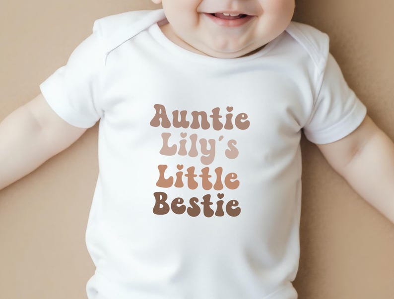 Neutral-toned personalised baby vest with retro-style "Auntie's Little Bestie" design, perfect for gifting from aunties to newborns.
