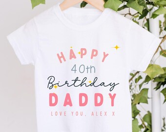 May include: A white short-sleeved t-shirt featuring the text HAPPY 40th Birthday DADDY in pink, grey, and black lettering, accented with small yellow star icons and the additional text LOVE YOU, ALEX X printed in pink at the bottom.