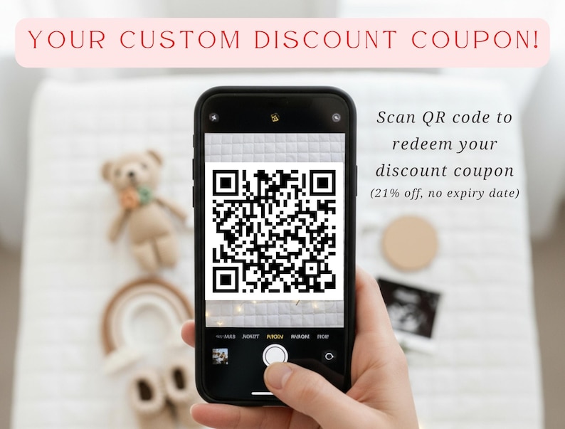 A person is holding a smartphone displaying a QR code, with a teddy bear in the background.