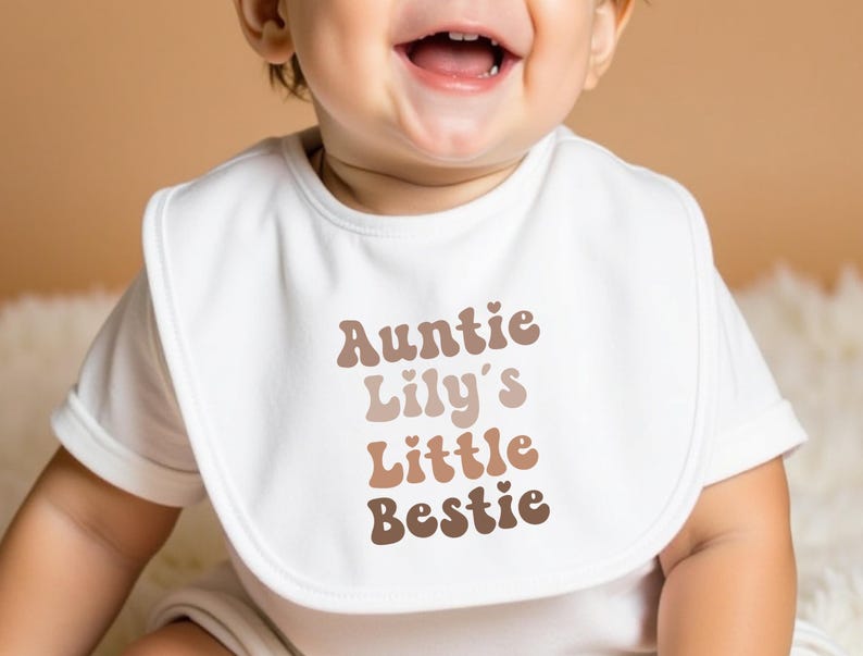 Cream-coloured baby bib featuring a retro "Auntie’s Little Bestie" message, ideal for a cute and practical gift from aunties.