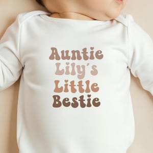 Unisex baby grow in soft beige with a vintage "Auntie’s Little Bestie" print, customisable for a stylish and sentimental outfit.