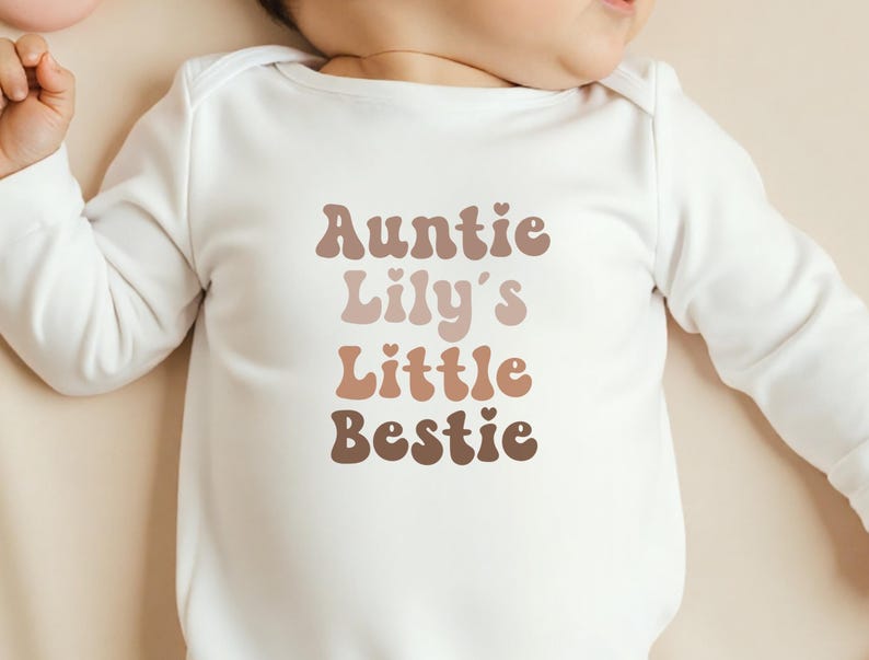 Unisex baby grow in soft beige with a vintage "Auntie’s Little Bestie" print, customisable for a stylish and sentimental outfit.