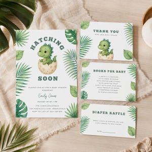 May include: A set of baby shower stationery featuring a green dinosaur hatching from an egg, decorated with watercolour tropical leaves. The cards include text for an invitation, a thank you note, a book request, and a diaper raffle entry.