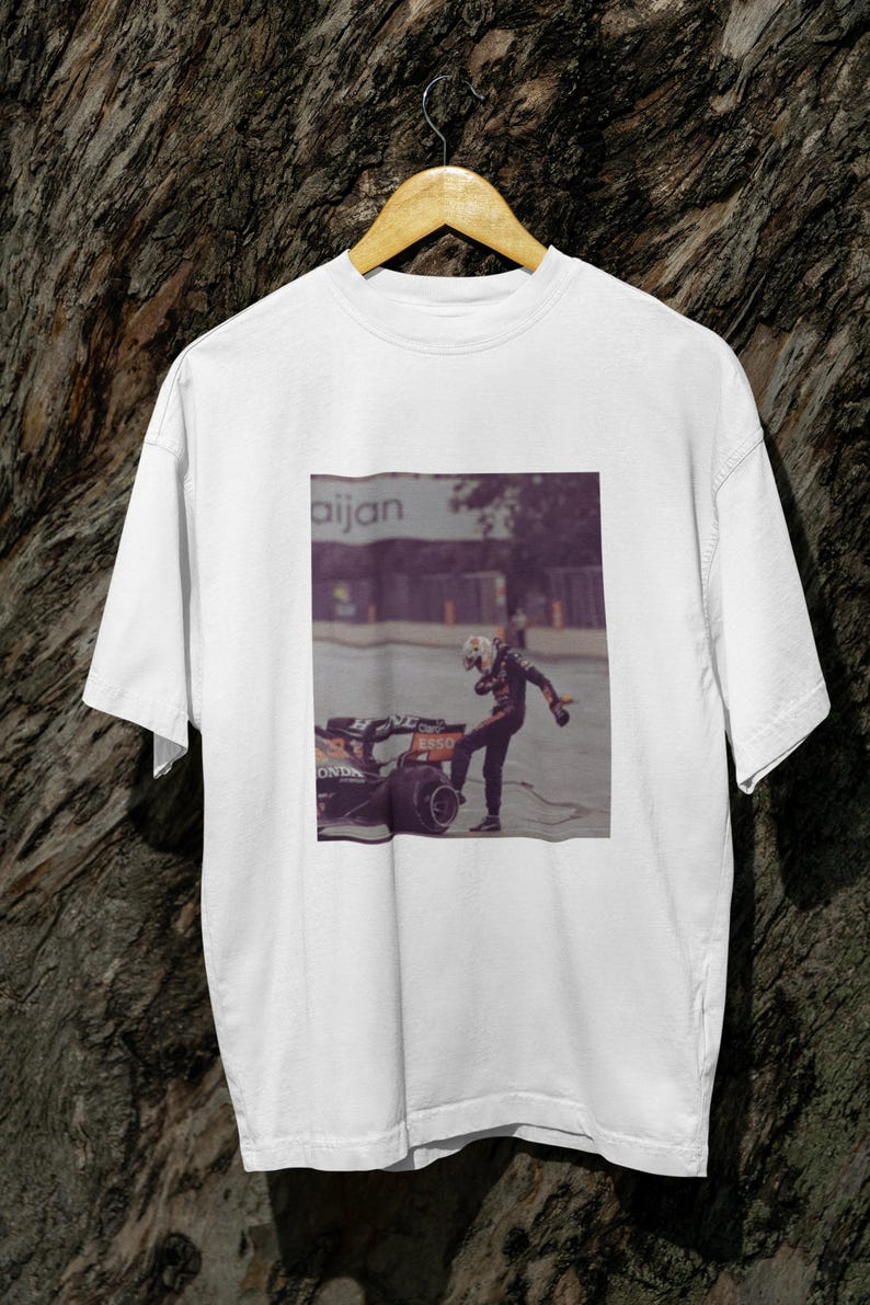 May include: White t-shirt with a graphic print of a race car driver celebrating on a racetrack. The text "aijan" is visible in the background.