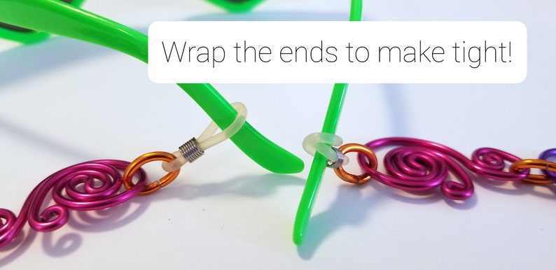 May include: Close-up of a green glasses frame with a pink and orange wire chain attached. The ends of the chain are wrapped around the glasses frame to make it tight. "Wrap the ends to make tight!" is written in white text on a white background.