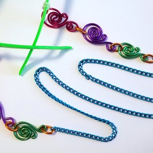 May include: A turquoise chain with colorful wire swirls attached to each end. The swirls are in shades of pink, purple, green, and orange.
