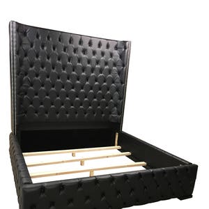 May include: A black leather upholstered bed frame with a tall headboard featuring a tufted design. The headboard is tall and has a curved shape. The bed frame has a wooden slat support system.