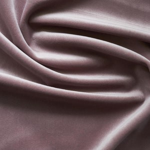 May include: A close-up of soft, smooth, dusty rose velvet fabric with gentle folds and wrinkles.
