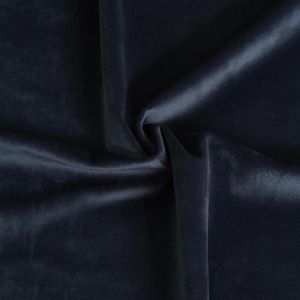 May include: Close-up of a dark blue velvet fabric with a soft, smooth texture. The fabric is draped and folded, creating a luxurious and elegant look.