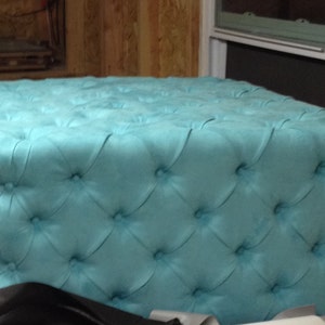 May include: A turquoise tufted ottoman with a square top and a button-tufted design.