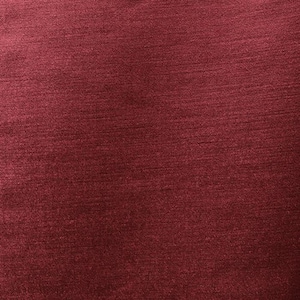 May include: A close-up of a deep red fabric with a subtle textured pattern. The fabric has a smooth, slightly shiny surface.