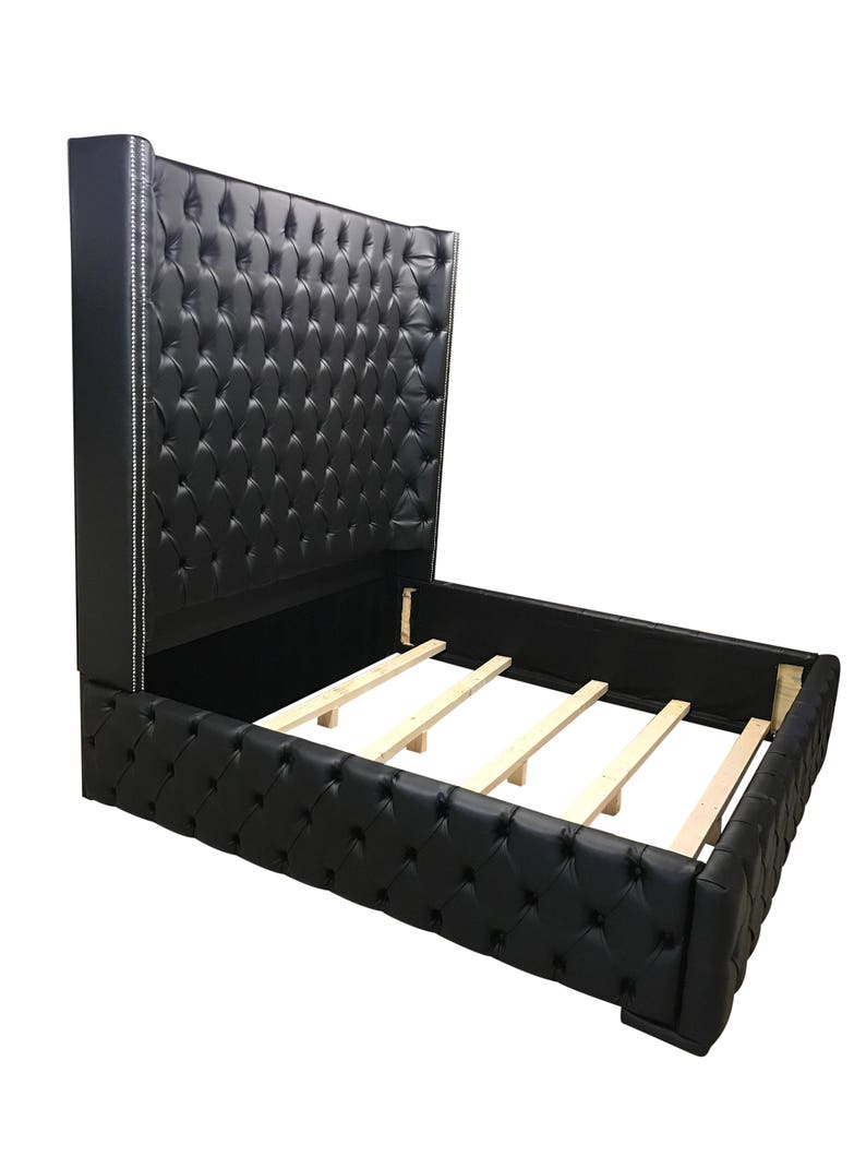 May include: A black upholstered bed frame with a tall headboard featuring a tufted design and silver nailhead trim. The bed frame has a wooden slat support system.