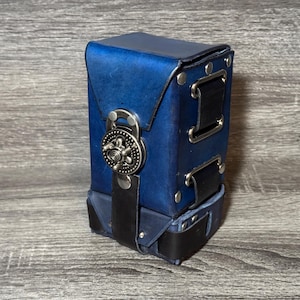May include: A blue leather box with a metal clasp and black leather straps. The box has a textured surface and is designed to hold small items.