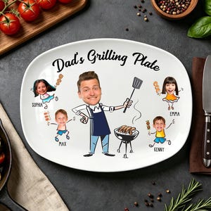 Puede incluir: Plato ovalado de cerámica blanca con el texto "Dad's Grilling Plate" y una ilustración de dibujos animados de un hombre asando a la parrilla con su familia. El plato está rodeado de tomates, hierbas y utensilios para asar.