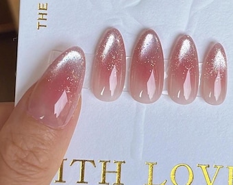 May include: A set of oval-shaped, press-on nails with a gradient design, transitioning from a light pink base to a shimmering silver tip. The card reads "The casual encounter is more gentle than the sunset" and "With Love".
