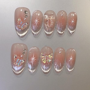 May include: Set of ten false nails with a clear base and a variety of designs, including butterflies, stars, and glitter.