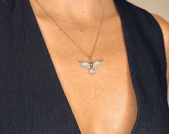 Pode incluir: Um colar de corrente de ouro com um pequeno pingente de pomba detalhado. A pomba é coberta por pequenas pedras transparentes.