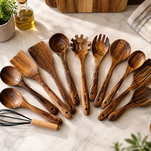 May include: A set of dark brown wooden kitchen utensils including various spoons, spatulas, a pasta fork, a slotted spoon, and a whisk with a wooden handle. Each wooden piece features a distinct grain pattern and a small feather icon engraving.