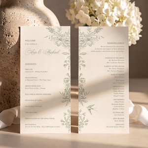 May include: Two tall, cream-colored wedding program cards featuring sage green floral illustrations and a small bird. The text includes "Welcome to the wedding of Ava & Michael," a ceremony schedule, and a list of the wedding party members.
