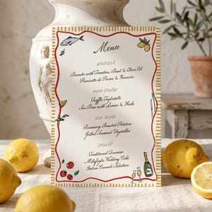 Könnte beinhalten: Eine cremefarbene Menükarte mit einem roten und goldenen Rand. Die Speisekarte listet Vorspeisen, Hauptgerichte, Beilagen und Desserts auf. Illustrationen von Zitronen, Fischen und Tomaten schmücken die Karte. Die Speisekarte enthält italienische Gerichte.
