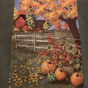 May include: A fall-themed decorative tapestry featuring a rural landscape. The artwork depicts a red farmhouse, a white fence, and a large tree with orange and yellow leaves. Pumpkins and sunflowers are in the foreground, with fallen leaves scattered on the ground.