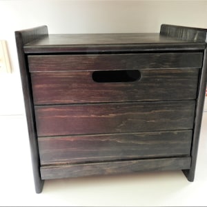 May include: A dark brown wooden storage box with a hinged lid and a cutout handle. The box has a rustic, farmhouse style.
