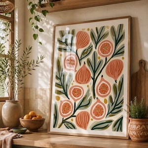 May include: A rectangular framed wall art print featuring a botanical illustration of whole and sliced figs in shades of coral and pink, interspersed with dark green and sage leaves and small yellow dots on a cream-colored background.