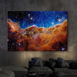 May include: A vibrant nebula with swirling orange, red, and blue hues against a dark blue starry background. The nebula resembles a mountain range with peaks and valleys.