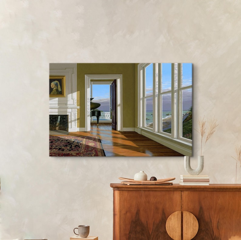 Op de afbeelding: Een ingelijste print van een kamerinterieur met uitzicht op de oceaan. De kamer heeft een piano, een open haard met een schilderij en een groot raam. Het kunstwerk toont een klassieke interieursc&egrave;ne met natuurlijk licht.