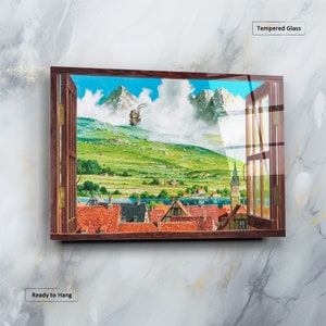 May include: A framed print of a painting depicting a small town nestled in a valley with a large mountain in the background. The painting is framed in a dark wood frame and has a glass front. The painting is titled "Tempered Glass" and is ready to hang.