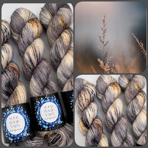 Könnte beinhalten: Stränge handgefärbter Wolle in Grau-, Creme- und Brauntönen. Die Wolle ist mit "YOUR MAGIC YARN hand dyed yarn" in einem blau-weißen Design gekennzeichnet. Das Bild enthält auch eine Nahaufnahme einer Pflanze mit verschwommenem Hintergrund.