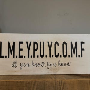 May include: White wooden sign with black lettering that reads "L.M.E.Y.P.U.Y.C.O.M.F. If you know, you know."