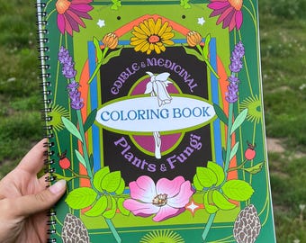 May include: A green spiral-bound coloring book titled "Edible & Medicinal Coloring Book Plants & Fungi" with floral and mushroom illustrations. The cover features a vibrant design with pink, yellow, and purple flowers. The text "by CARRIIT FARMS" is at the bottom.