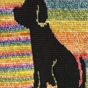 May include: A black silhouette of a dog sitting, embroidered on a colorful, rainbow-striped background. The dog's outline is clearly defined against the vibrant, textured fabric, creating a striking contrast. The background features horizontal stripes of various colors.