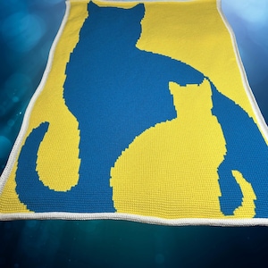 Puede incluir: Una manta de ganchillo con una silueta de gato azul sobre un fondo amarillo.